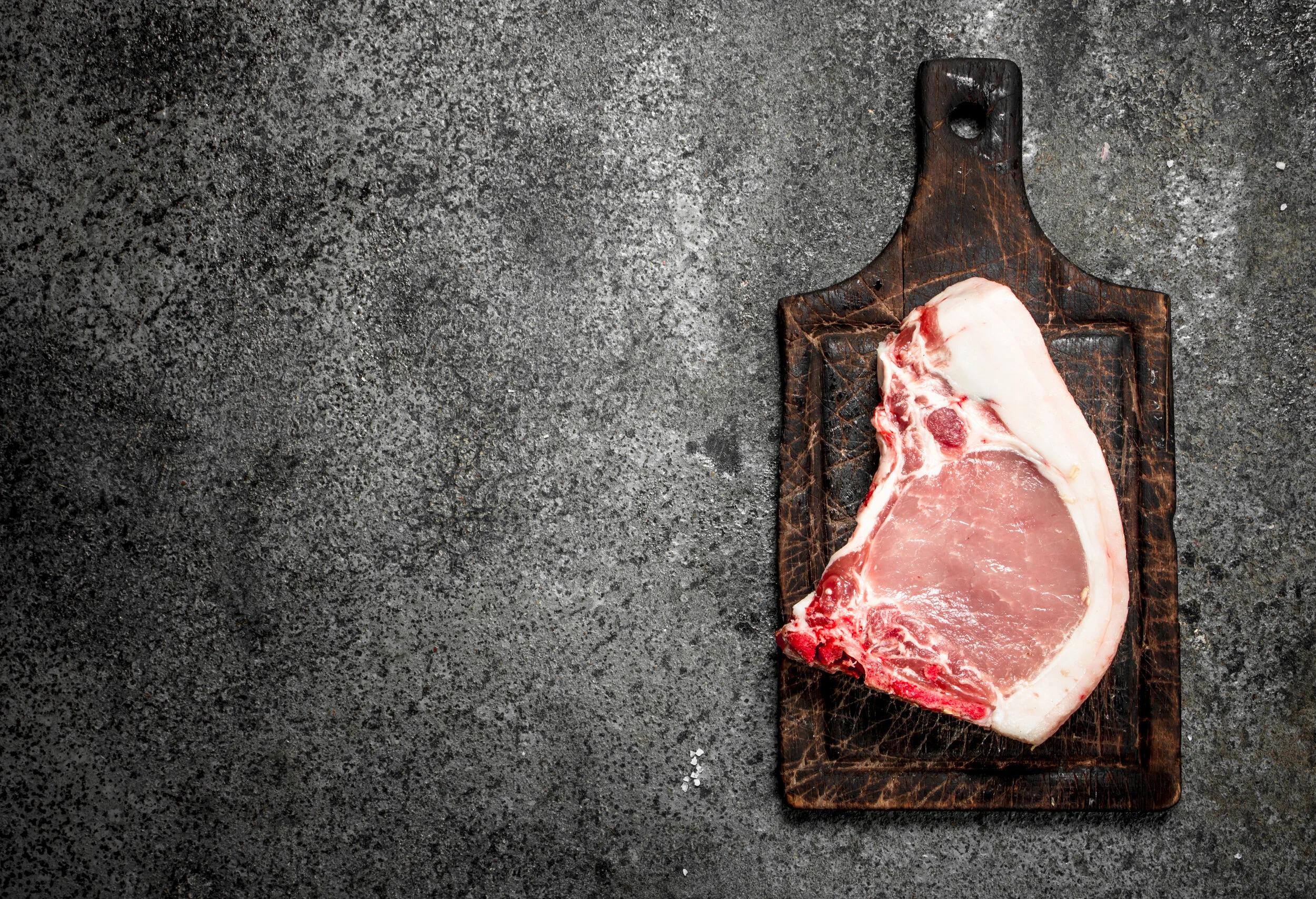 pork+chop Succulent pulled pork on a wooden cutting board, showcasing tender, shredded meat with a crispy outer layer. A fork rests beside the meat, highlighting its juicy texture and rich seasoning.